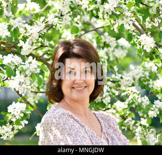 Lächelnde Frau in blühender Apfelbaum Stockfoto