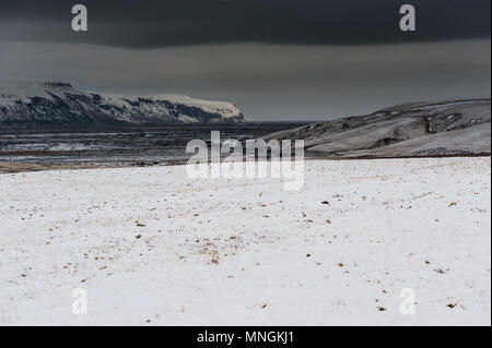 Melancholische Landschaft mit Wolke bedeckte Himmel und Schneefall in isländischer Land zurück, April 2018 Stockfoto