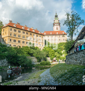 Rafting auf der Moldau in Cesky Krumlov mit seiner Burg, während die Leute im Freien in einer Bar/Restaurant gesellig sind. Tschechische Republik. Stockfoto