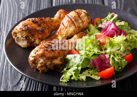 Gegrillte Chicken Drumsticks und frischem Gemüse auf schwarzem Hintergrund closeup. Horizontale Stockfoto