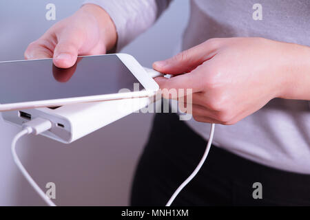 Die Frauen hand Halten Sie das Telefon sowie das Ladegerät powerbank Smart Phone, und ist das Verknüpfen, Energie Stockfoto