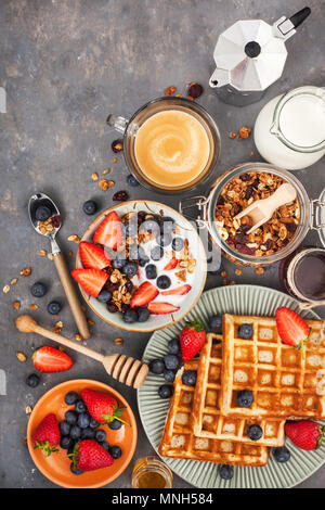 Gesundes Frühstückstisch mit Getreide Müsli, Milch, frische Beeren, Kaffee und Waffeln, Ansicht von oben Stockfoto