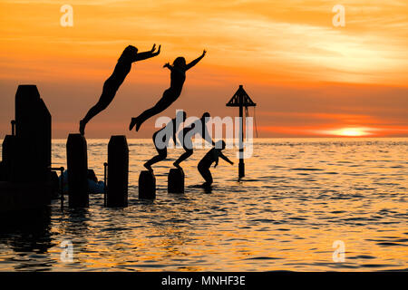 Aberystwyth Wales UK, Donnerstag, 17. Mai 2018 Deutschland Wetter: Bei Sonnenuntergang am Ende einer glorreichen Tag der warmen Frühlingssonne, eine Gruppe von Studenten sind wie Sie tauchen und springen Sie in das klare Wasser aus dem hölzernen Pier in Aberystwyth an der Westküste von Wales Foto © Keith Morris/Alamy Leben Nachrichten Silhouette Stockfoto