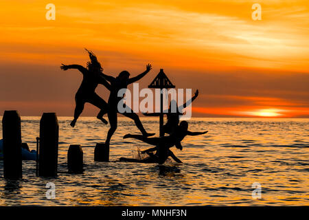 Aberystwyth Wales UK, Donnerstag, 17. Mai 2018 Deutschland Wetter: Bei Sonnenuntergang am Ende einer glorreichen Tag der warmen Frühlingssonne, eine Gruppe von Studenten sind wie Sie tauchen und springen Sie in das klare Wasser aus dem hölzernen Pier in Aberystwyth an der Westküste von Wales Foto © Keith Morris/Alamy Leben Nachrichten Silhouette Stockfoto