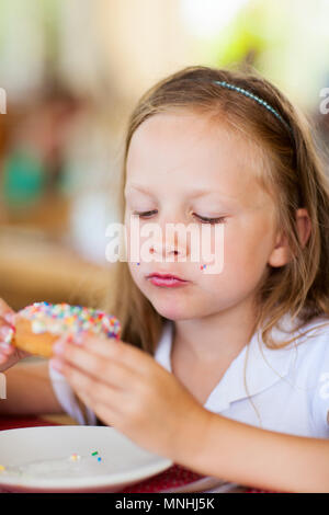 Adorable kleine Mädchen genießen Donut Essen im Cafe Stockfoto