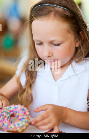 Adorable kleine Mädchen genießen Donut Essen im Cafe Stockfoto