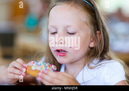 Adorable kleine Mädchen genießen Donut Essen im Cafe Stockfoto