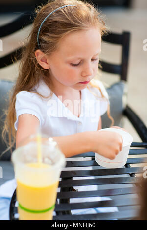 Kleines Mädchen essen ein Eis im Café im Freien Stockfoto