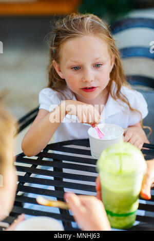 Kleines Mädchen essen ein Eis im Café im Freien Stockfoto