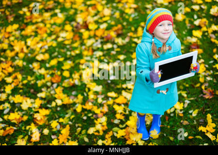 Adorable kleine Mädchen, dass leere Tafel am schönen Herbst Park Stockfoto