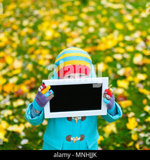Adorable kleine Mädchen, dass leere Tafel am schönen Herbst Park Stockfoto