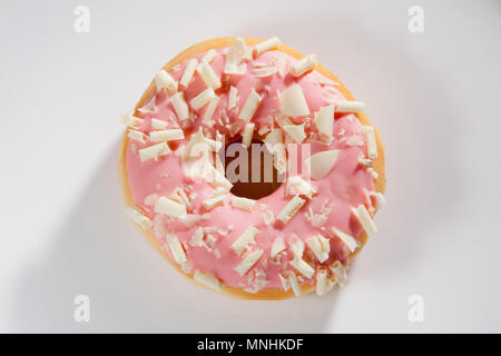 Donut mit orange Glasur und bunten Streuseln auf weißem Hintergrund. Ansicht von oben. Stockfoto