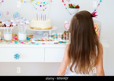 Adorable kleine Mädchen mit Princess Crown auf einer Geburtstagsfeier in der Nähe von Dessert Tabelle Stockfoto