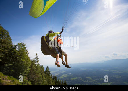 Zwei Gleitschirme auf Tandem sind vom Dobrca Berg. Man hält ein selfie Stick mit Action Kamera, in der Nähe von begunje und Radovljica, Obere Krain, Slowenien Stockfoto