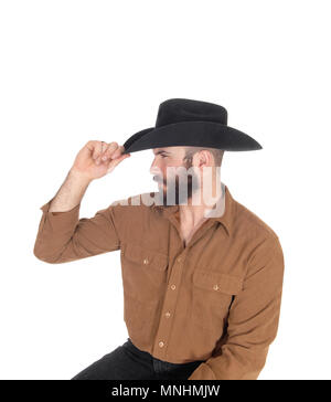 Ein junger Mann sitzt auf einem Stuhl im Profil trägt einen schwarzen Cowboyhut und Weg suchen, auf weißem Hintergrund Stockfoto