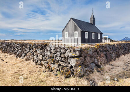 Budir Kirche, wie die Kleinen Schwarzen Kirche bekannt, auf der Halbinsel Snaefellsnes, West Island, mit einer Trockenmauer aus Lava. Stockfoto