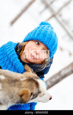 Adorable kleine Mädchen, dass eine Husky Welpe in Lappland, Finnland Stockfoto