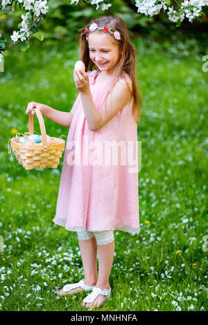 Adorable kleine Mädchen spielen mit Ostereier in einem blühenden Garten Frühling Stockfoto