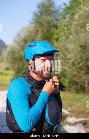 Lächelnd kayaker mit Bart setzen auf Sicherheit Helm vor Kajak in Fluss Soca in der Nähe von Bovec, slowenischer Küste, Slowenien Stockfoto