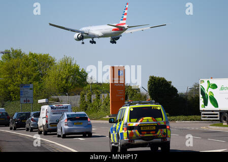 American Airlines Boeing 777 Jet Flugzeug landet am London Heathrow Airport UK in blauem Himmel über Polizeiauto und Parkschild Stockfoto