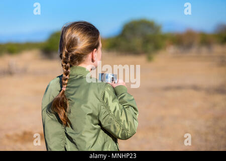 Adorable kleine Mädchen in Südafrika Safari mit Tasse heiße Schokolade auf der Suche nach Zebras auf einer Entfernung Stockfoto