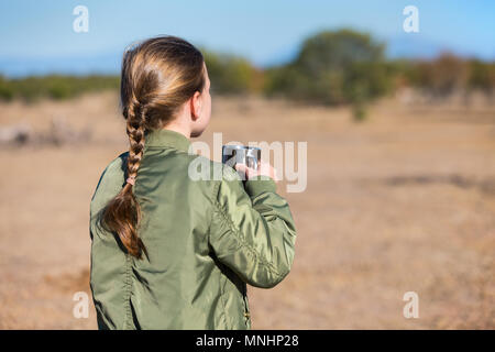 Adorable kleine Mädchen in Südafrika Safari mit Tasse heiße Schokolade auf der Suche nach Zebras auf einer Entfernung Stockfoto