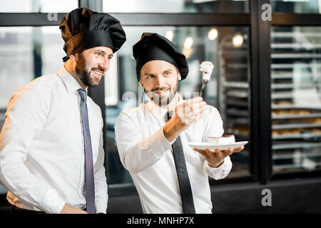 Zwei elegante Konditoren oder Chef kocht die Kontrolle der Qualität der leckeren Kuchen in der Bäckerei Büro Stockfoto