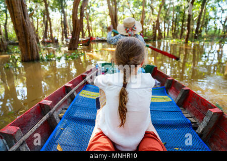 Zurück Blick auf ein kleines Mädchen haben eine Bootsfahrt auf überschwemmten Wald in Kambodscha Stockfoto