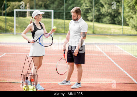 Junges Paar stehen zusammen mit rackets Entspannung nach der Partie Tennis auf dem Tennisplatz Stockfoto