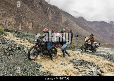 Nubra Tal, Indien - 29. Juni 2017: Radfahrer, die sich gegenseitig helfen den Fluss, der aus schmelzendem Schnee im Himalaya zu überqueren, Ladakh region, Indi Stockfoto