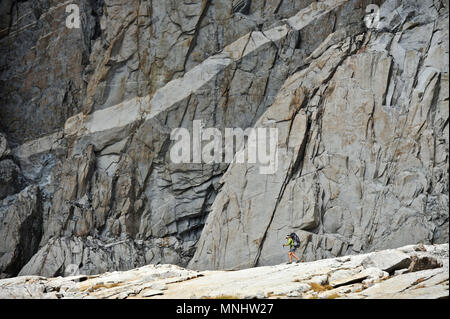 Backpacker Wanderungen unter einer granitmauer in Palisade Becken auf einer zwei-wöchigen Trek der Sierra Hohe Weg in Kings Canyon National Park in Kalifornien. Die 200 km Route etwa Parallels die beliebte John Muir Trail durch die Sierra Nevada von Kalifornien von Kings Canyon National Park, Yosemite National Park. Stockfoto