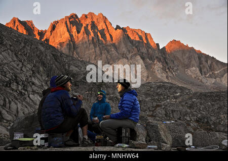 Backpackers Essen mit Scheinwerfern am Lager sitzen auf dem Barrett Seen in Palisade Becken auf einer zwei-wöchigen Trek der Sierra Hohe Weg in Kings Canyon National Park in Kalifornien. Die 200 km Route etwa Parallels die beliebte John Muir Trail durch die Sierra Nevada von Kalifornien von Kings Canyon National Park, Yosemite National Park. Sonnenuntergang leuchtet im Norden Palisade im Hintergrund. Stockfoto