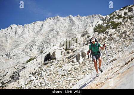 Backpackers Wanderung hinunter die granitplatten der Gabbot Pass auf einer zwei-wöchigen Trek der Sierra Hohe Weg in der John Muir Wildnis in Kalifornien. Die 200 km Route etwa Parallels die beliebte John Muir Trail durch die Sierra Nevada von Kalifornien von Kings Canyon National Park, Yosemite National Park. Stockfoto