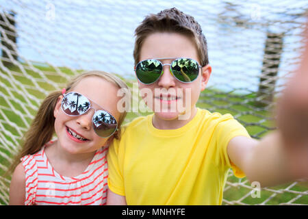 Teenager unter selfie mit seiner kleinen Schwester im Freien auf Sommer Tag Stockfoto