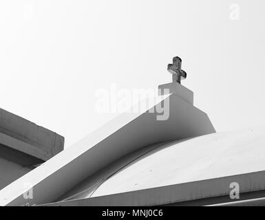 Ein Teil des Daches mit einem Kreuz gegen den Himmel in Schwarz und Weiß Stockfoto