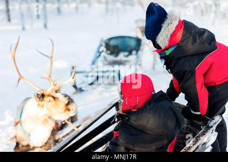Familie mit Kindern an Rentier Safari im Winter Wald in Lappland Finnland Stockfoto