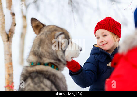 Adorable kleine Mädchen mit einem Kuscheln mit Husky Schlittenhund in Lappland Finnland Stockfoto