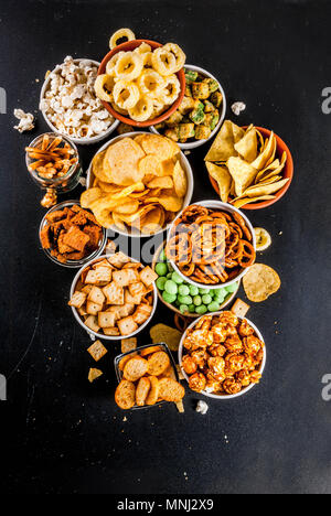 Variation verschiedener ungesunden Snacks Kekse, süßes Popcorn gesalzen, Tortillas, Muttern, Strohhalme, bretsels, zurück Tafel Platz kopieren Stockfoto