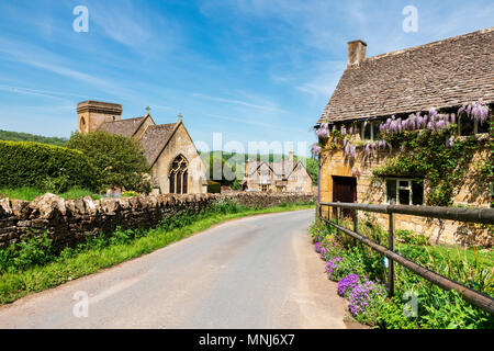 Snowshill, Cotswolds, England, UK. Wisteria Blumen auf einem Haus neben der Kirche in einem Cotswold Village. Stockfoto