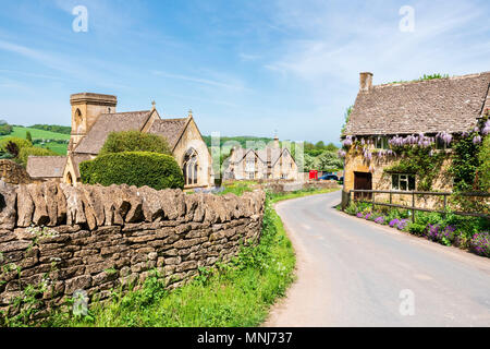 Snowshill, Cotswolds, England, UK. Wisteria Blumen auf einem Haus neben der Kirche in einem Cotswold Village. Stockfoto