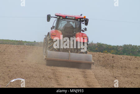 Landwirt rolling ein Feld auf einem Bauernhof in Irland, mit einer schweren Walze mit einem Traktor vor der Aussaat ein Weizen gezogen. Stockfoto