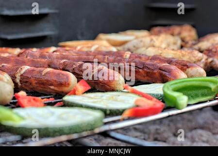 Leckeres Essen, Ernährung, kulinarischen und Grill Konzept: gegrillte Würstchen, Hähnchen Schenkel und Gemüse auf einem Grill. Stockfoto