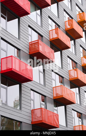 Leuchtend rot und orange Metalldrähte hervorstehenden Balkonen in Grau modernes hohes Gebäude mit großen Fenstern und avantgardistische Architektur in Pearl Distri Stockfoto