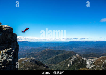 BASE Jumper beim freien Fall gegen den klaren blauen Himmel direkt nach dem Sprung von der Oberseite der Franzose's Gap, Tasmanien, Australien Stockfoto