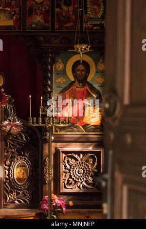 Strahlen von Licht onn ein Symbol Jesu Christi in einer orthodoxen Kirche in Bulgarien, mit Kerzen vor dem Es leuchtet Stockfoto