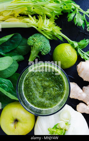 Detox gesunden grünen Smoothie in einem Glas auf schwarzen Hintergrund mit Zutaten: Spinat, Sellerie, Ingwer, Fenchel, Kalk, Brokkoli und Apple. Ernährung, Gesundheit, Stockfoto