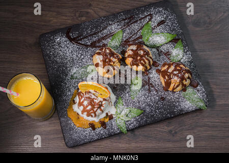 Eine Kugel Eis auf einem Stein mit einem orangefarbenen Glas Saft Stockfoto