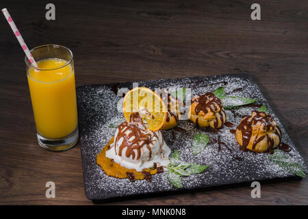 Eine Kugel Eis auf einem Stein mit einem orangefarbenen Glas Saft Stockfoto