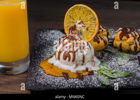 Eine Kugel Eis auf einem Stein mit einem orangefarbenen Glas Saft Stockfoto