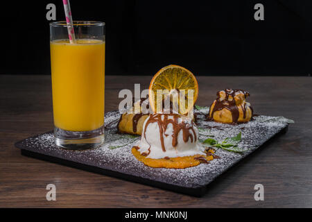 Eine Kugel Eis auf einem Stein mit einem orangefarbenen Glas Saft Stockfoto